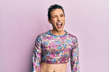 Makyaj elbisesi giymiş yakışıklı bir adam kameraya seksi bir ifadeyle bakıyor, neşeli ve mutlu bir yüz.. 