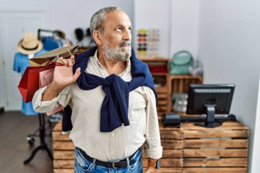 Yakışıklı son sınıf öğrencisi butik dükkanında alışveriş torbaları tutuyor gülümsüyor ve yan tarafa bakıyor ve düşünüyor.. 