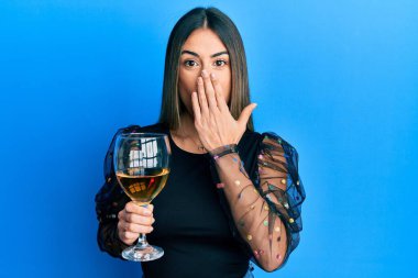 Genç İspanyol kadın bir bardak kırmızı şarap içerken ağzını eliyle kapadı, şok oldu ve hata yapmaktan korktu. şaşırmış ifade 