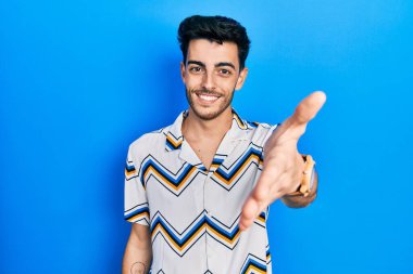 Gündelik kıyafetler giyen, neşeli gülümseyen, yardım eli uzatan ve kabul gören genç İspanyol bir adam.. 