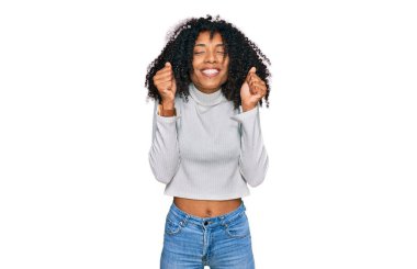 Başarı için heyecanlı, kollarını kaldırmış ve gözleri kapalı zaferi kutlayan gündelik giysiler giyen Afro-Amerikalı genç kız. Kazanan konsept. 