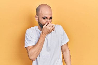 Gündelik beyaz tişört giyen genç kel bir adam pis ve iğrenç bir koku alıyor, dayanılmaz bir koku, nefesini burnunda tutuyor. Kötü kokuyor. 