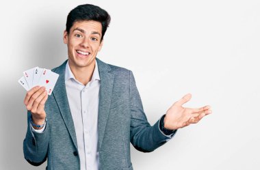 Genç İspanyol iş adamı poker oynuyor başarıyı mutlu bir gülümsemeyle kutluyor ve kazanan el kaldırarak ifade ediyor 