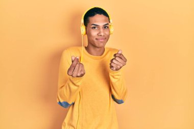 Genç Afro-Amerikalı adam kulaklık takıp müzik dinliyor. Elleriyle para hareketi yapıyor. Maaş istiyor. 