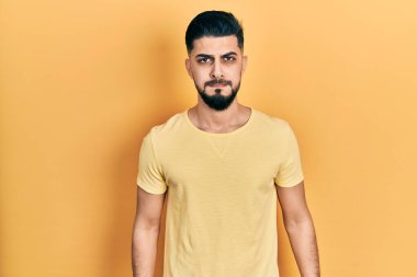 Sakallı, sıradan sarı tişörtlü, komik suratlı yakışıklı bir adam. Havayla şişmiş ağız, çılgın bir ifade.. 