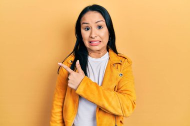 Burnu delinmiş, sarı deri ceketli güzel İspanyol bir kadın endişeli ve endişeli bir ifade takınıyor. 