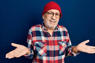 Yakışıklı, hippi görünümlü, şapkasız, kafası karışmış, kolları ve elleri havada bir adam. şüphe kavramı. 