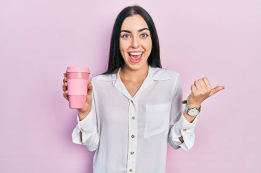 Mavi gözlü güzel bir kadın bir fincan kahve içerken başparmağını kaldırıyor ve gülümsüyor. 