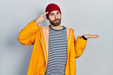 Sarı yağmurluk giyen, sakallı beyaz bir adam avuç içi açık fotokopi alanı ve alnını göstermekten rahatsız oluyor. Bunu bir düşün.. 