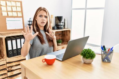 Ofiste çalışan genç esmer kadın dizüstü bilgisayarından korkuyor ve korkudan dehşete düşüyor. El hareketlerini durdur, şok içinde bağır. panik konsepti. 