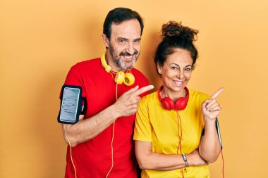 Orta yaşlı bir çift İspanyol kadın ve erkek spor giyer ve kol bandı takar gülümser ve kameraya bakar.. 