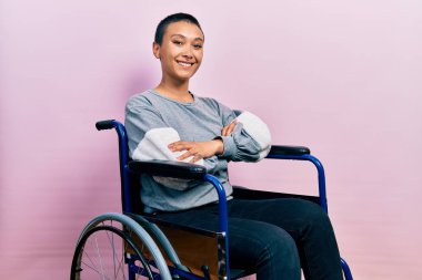Tekerlekli sandalyede oturan, mutlu yüzlü, kollarını kavuşturup kameraya bakan güzel İspanyol kadın. pozitif kişi. 