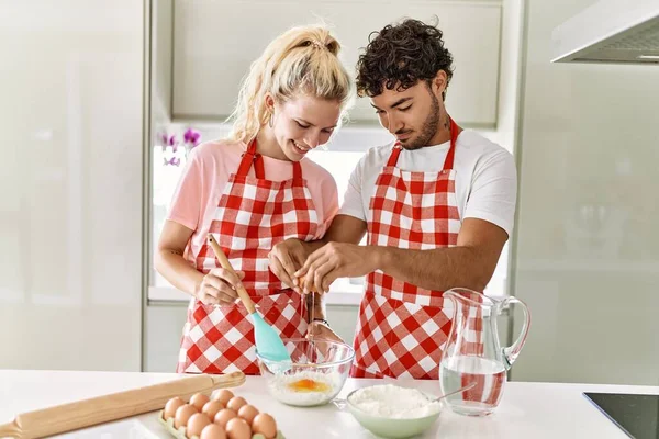 Pareja Joven Sonriendo Feliz Mezclando Ingredientes Para Hacer Masa Para —  Fotos de Stock