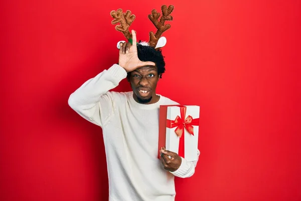Joven Afroamericano Con Sombrero Navidad Venado Sosteniendo Regalo Burlándose Gente — Foto de Stock