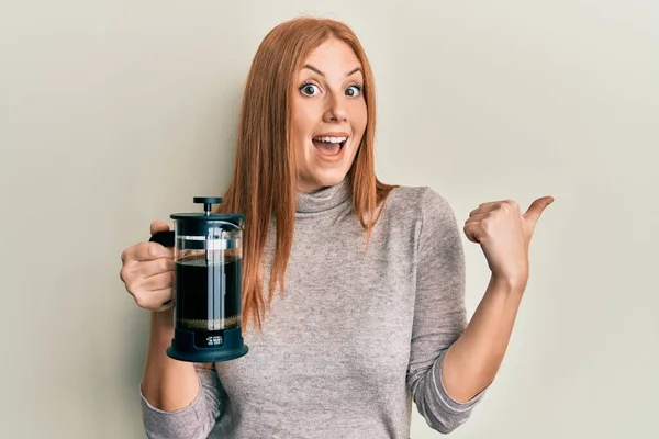 Joven Mujer Irlandesa Sosteniendo Cafetera Francesa Señalando Pulgar Hacia Lado — Foto de Stock