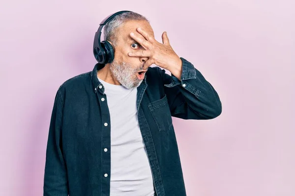Hombre Mayor Guapo Con Barba Escuchando Música Usando Auriculares Asomándose —  Fotos de Stock
