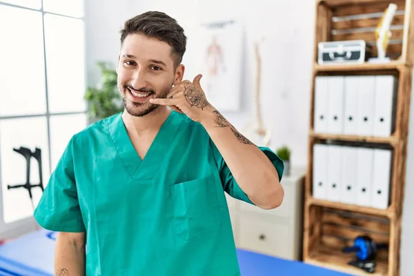 Ağrı Kesici Kliniğinde Çalışan Genç Bir Fizyoterapist Gülümsüyor Telefonla Parmaklarıyla — Stok fotoğraf