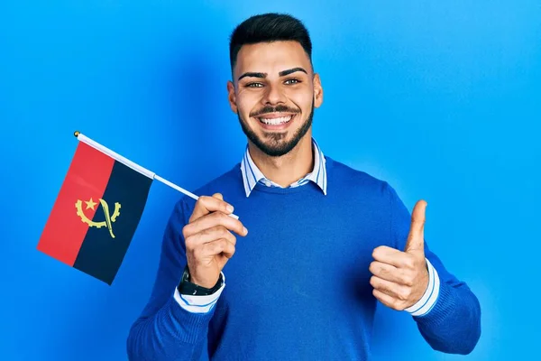 Joven Hombre Hispano Con Barba Sosteniendo Bandera Angola Sonriendo Feliz —  Fotos de Stock