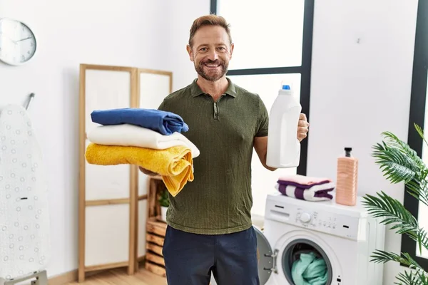 Hombre Mediana Edad Sosteniendo Ropa Limpia Botella Detergente Sonriendo Con — Foto de Stock