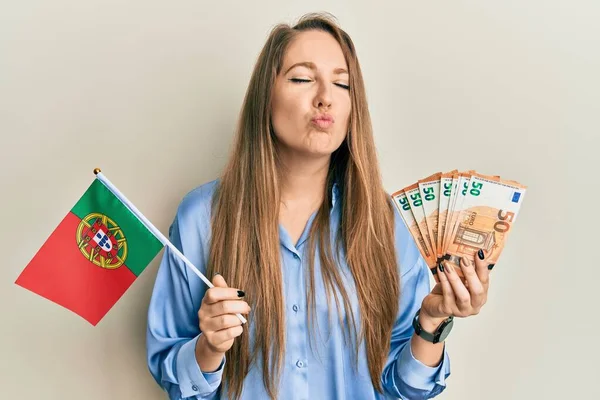 年轻的金发女子举着葡萄牙国旗和欧元钞票 看着摄像机拍打着一个吻 看起来既可爱又性感 爱的表达 — 图库照片