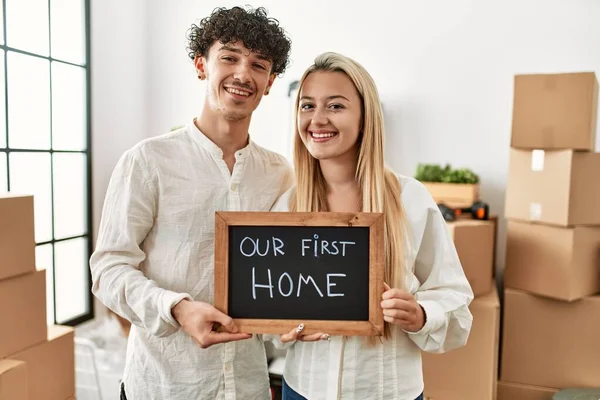 Young Beautiful Couple Smiling Happy Holding Blackboard Our First Home — Stock Photo, Image