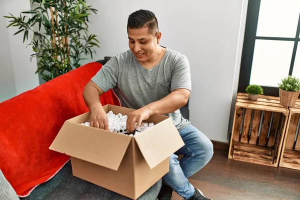Jovem Hispânico Sorrindo Feliz Unboxing Caixa Papelão Sentado Sofá Casa — Fotografia de Stock