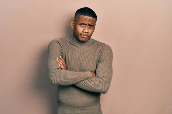 Young black man wearing casual turtleneck sweater skeptic and nervous, disapproving expression on face with crossed arms. negative person.