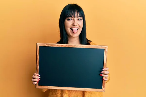 Joven Mujer Hispana Sosteniendo Pizarra Sacando Lengua Feliz Con Expresión — Foto de Stock