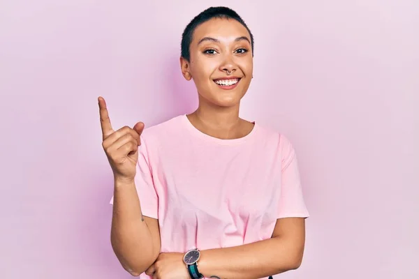成功したアイデアで指を指してカジュアルなピンクのTシャツを着て短い髪を持つ美しいヒスパニック系の女性 興奮して幸せよ 第1位 — ストック写真