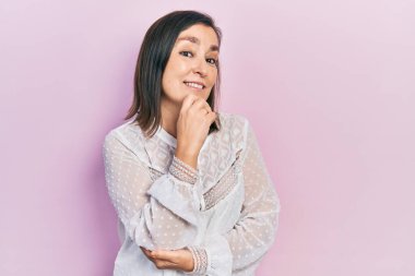 Orta yaşlı İspanyol kadın gündelik kıyafetler giyip kameraya bakıyor kollarını kavuşturup gülümseyerek ve çenesini kaldırarak. Olumlu düşünmek. 