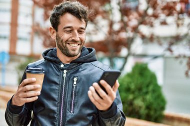 Yakışıklı, sakallı, dışarıda mutlu gülümseyen akıllı telefon kullanan adam.