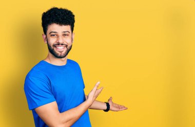 Mavi tişörtlü, sakallı genç Arap adam gülümseyerek içeri girmeye davet ediyor. 