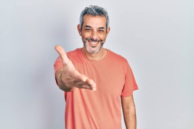 Yakışıklı, orta yaşlı, gri saçlı, sıradan tişörtlü, dostça gülümseyen ve selamlaşan bir adam. başarılı iş. 