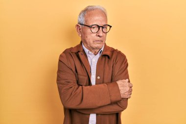 Gri saçlı, günlük ceket giyen, gözlüklü, şüpheci ve gergin, yüzünde çapraz kollu tasvip etmeyen bir ifade olan son sınıf öğrencisi. negatif kişi. 