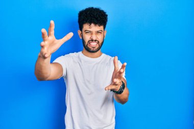 Sakallı, beyaz tişörtlü genç Arap adam öfkeyle bağırıyor, elleri boğmaya çalışıyor, deli gibi bağırıyor. 