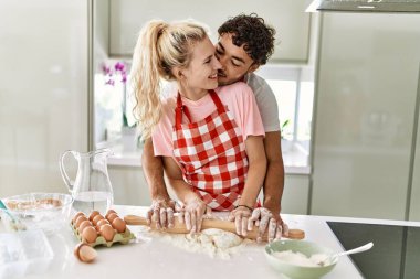 Mutfakta elleri ile hamuru yoğurmaktan mutlu gülümseyen genç çift..