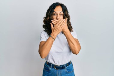 Gündelik beyaz tişört giyen orta yaşlı İspanyol kadın yanlışlıkla elleriyle ağzını kapatırken şok oldu. gizli kavram. 