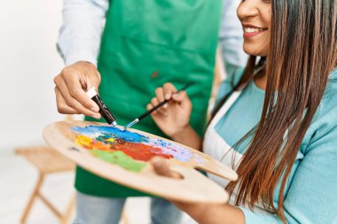 Resim stüdyosunda gülümseyen genç Latin ressam çift.