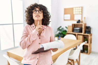 Ofiste iş elbisesi giyen genç bir ortadoğulu kadın şüphe üzerine yoğunlaşmıştı. Parmakları çenesinde ve yukarı bakıyordu. 
