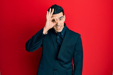 Yakışıklı İspanyol adam iş kıyafetleri giyiyor. El hareketleriyle gülümsüyor, gözleriyle gülen parmaklarının arasından bakıyor.. 