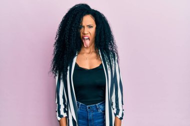 Orta yaşlı Afro-Amerikan kadın günlük kıyafetler giyip dillerini komik bir ifadeyle dışarı çıkarıyor. duygu kavramı. 