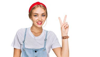 Gündelik kıyafetler giyen genç beyaz kız iki numarayı gösterip işaret ederken kendinden emin ve mutlu bir şekilde gülümsüyor.. 