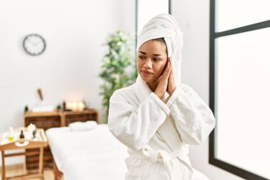 Havlu ve bornoz giymiş genç esmer kadın güzellik merkezinde ayakta uyur, yorgun düşler görür ve elleri ile birlikte poz verir, gözleri kapalı gülümserdi.. 