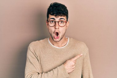 Gündelik kıyafet ve gözlük takan genç İspanyol adam parmaklarını yana çevirerek şaşırdı, ağzı açık hayret içinde kaldı.. 