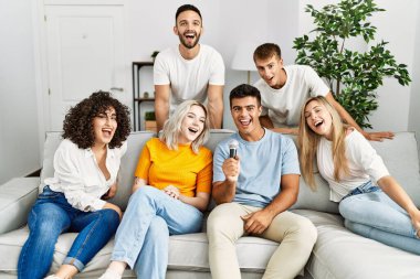 Bir grup genç arkadaş evde mikrofon kullanarak şarkı söylüyor..