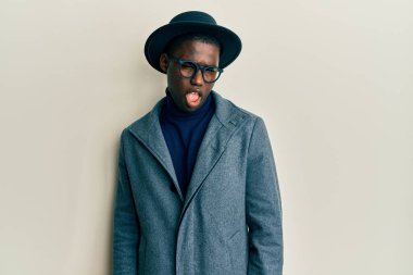 Zarif tarzda giyinmiş genç Afro-Amerikalı adam kameraya seksi bir ifadeyle bakıyor, neşeli ve mutlu bir yüzle.. 