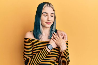 Sıradan çizgili gömlek giyen genç modern bir kız elleri göğsünde gülümseyen, gözleri kapalı, yüzünde minnet dolu bir jest ile. sağlık kavramı. 