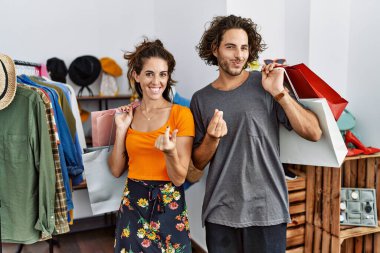 Satış mağazasında alışveriş torbaları tutan genç İspanyol bir çift. Elleriyle para hareketi yapıyor. Maaş ve milyonerlik işleri istiyor. 