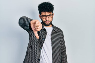 Sakallı, gözlüklü, mutsuz, kızgın, reddedilmiş ve olumsuz jestli genç bir Arap. kötü ifade. 