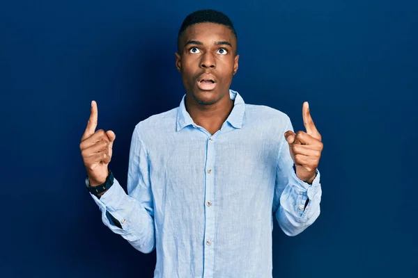 若いアフリカ系アメリカ人の男性は カジュアルな服を着て驚きと驚きを見上げ 指と腕を上げて — ストック写真